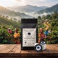 Jamaica Blue Mountain Coffee Pods 100% Pure Single-serve by Roast Theory. A black stand-up coffee bag labeled Roast Theory Jamaica Blue Mountain sits on a wooden table, with two coffee pods in front. Behind it is a scenic backdrop of coffee growers harvesting coffee in green hills and misty mountains.